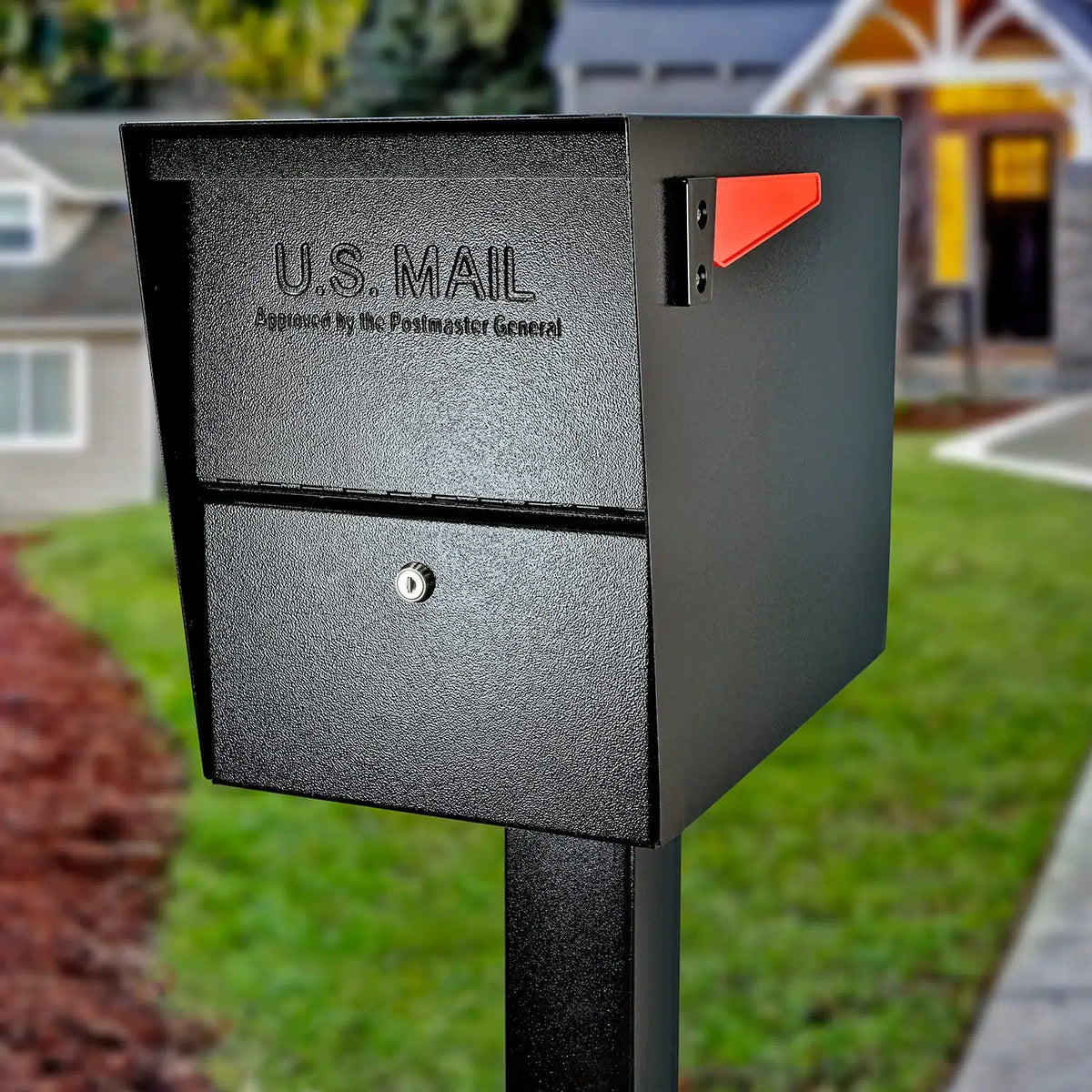 Black locking package mailbox on a post in front of a house